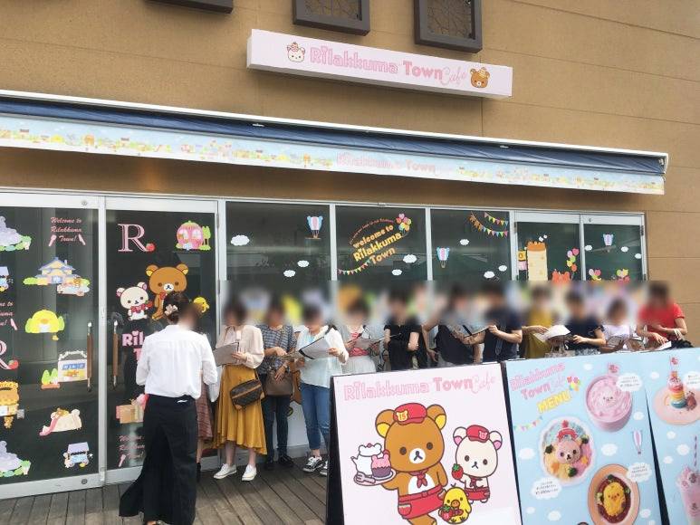 People waiting in line outside the Rilakkuma Town Café in Osaka, Japan, with an exterior decorated in cute character illustrations