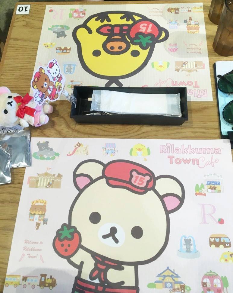 Rilakkuma-themed table setting at the café in Osaka, featuring 15th anniversary placemats, utensils, and plush character decorations