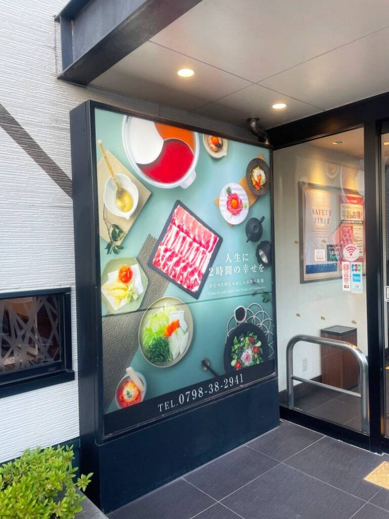 Kinnobuta entrance signboard showing shabu-shabu ingredients and the message "Two hours of happiness in life"