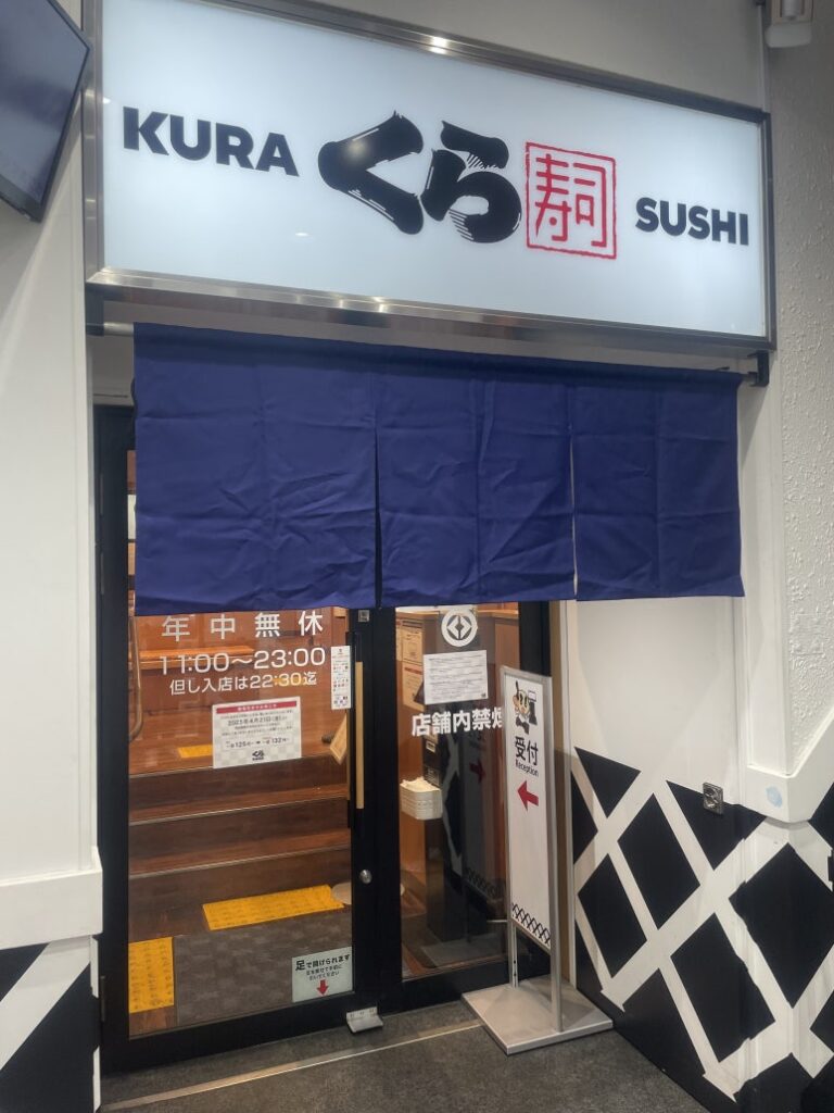 Entrance of Kura Sushi restaurant with blue curtain and signboard