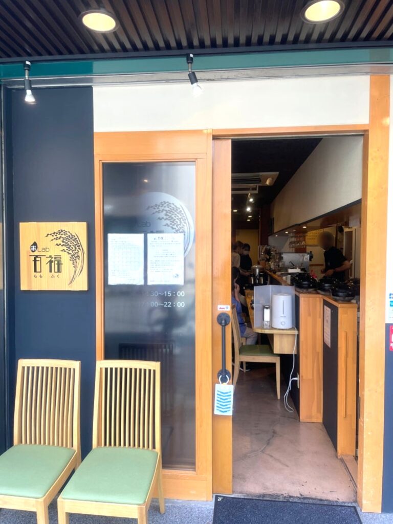 Front entrance of Momofuku with wooden door and counter seats visible