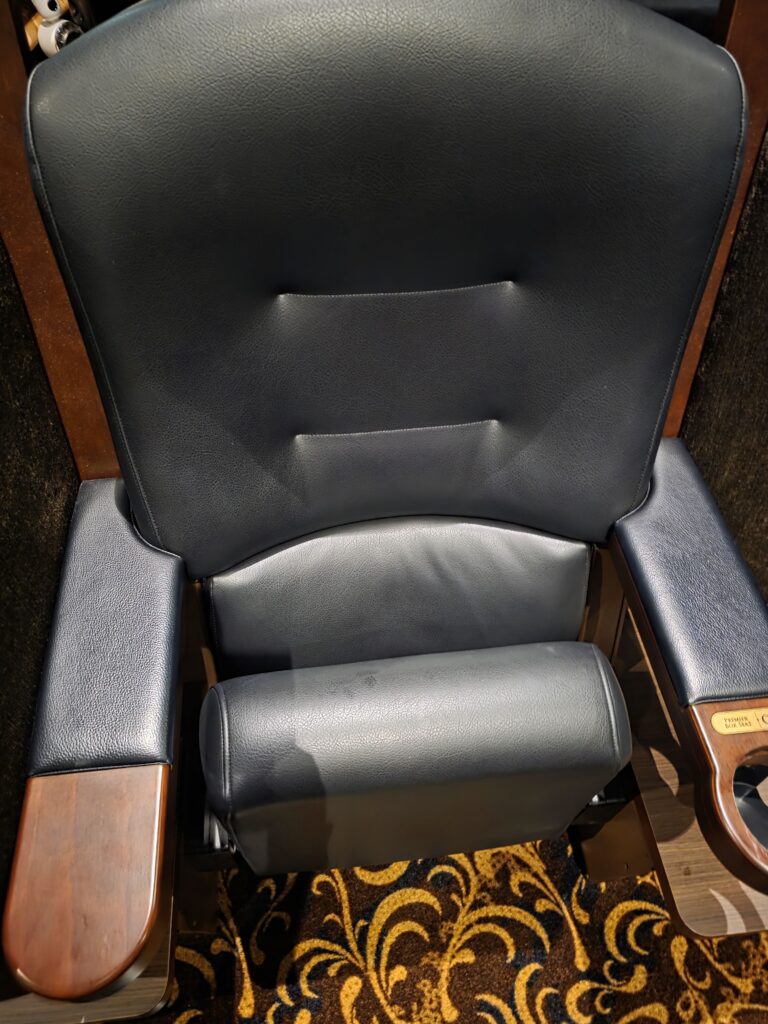 Front view of a single leather premium box seat with wooden armrests