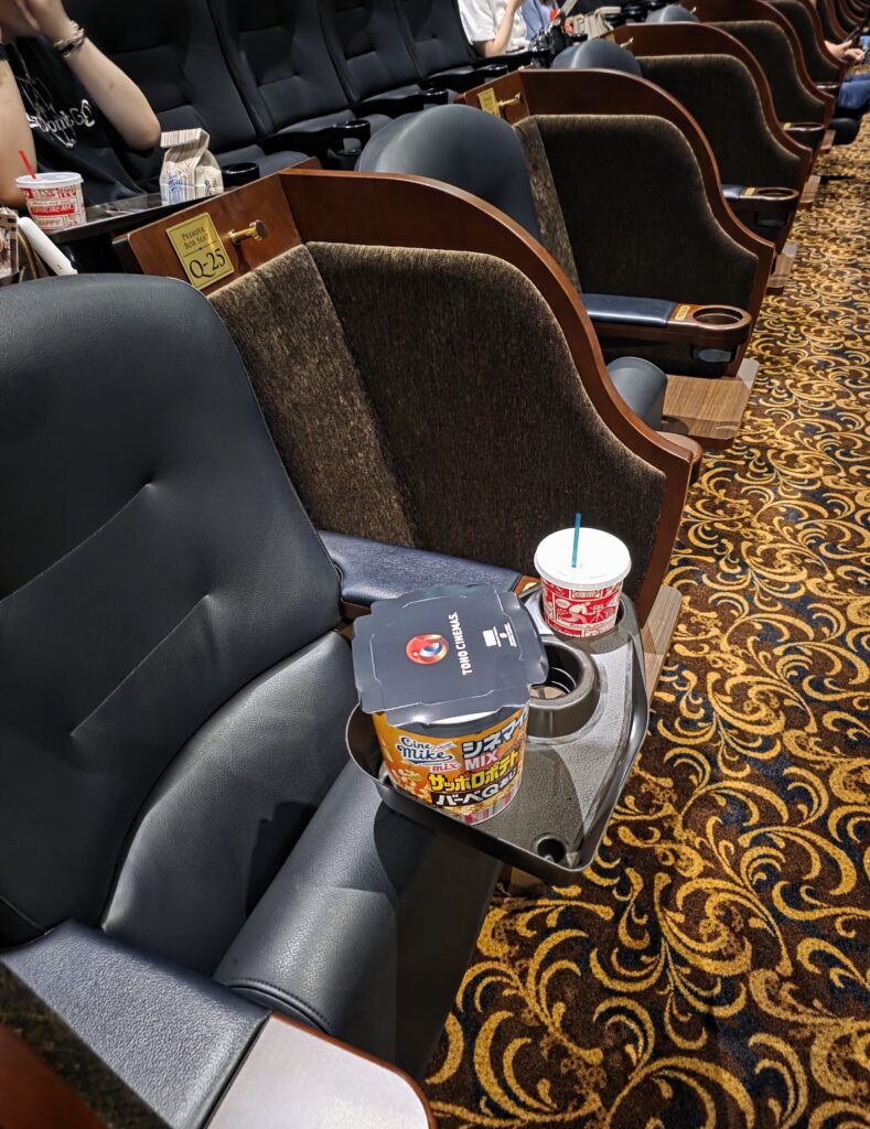 Wide view of premium box seats in Screen 1 showing armrests and tray tables
