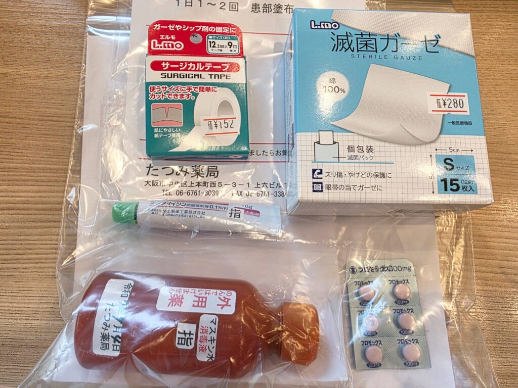 Medications purchased at a Japanese pharmacy for a finger cut: surgical tape, sterile gauze, antibiotic ointment, disinfectant, and oral antibiotics