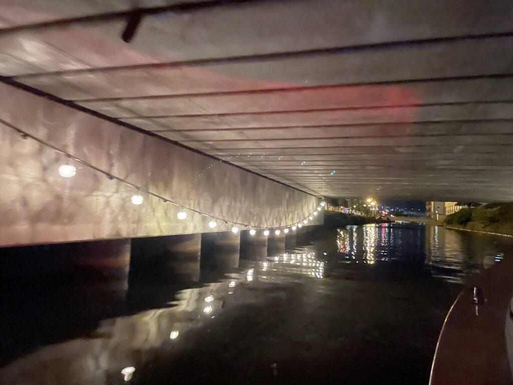 View from the start of the Otaru Canal night cruise, passing under a lit-up bridge.