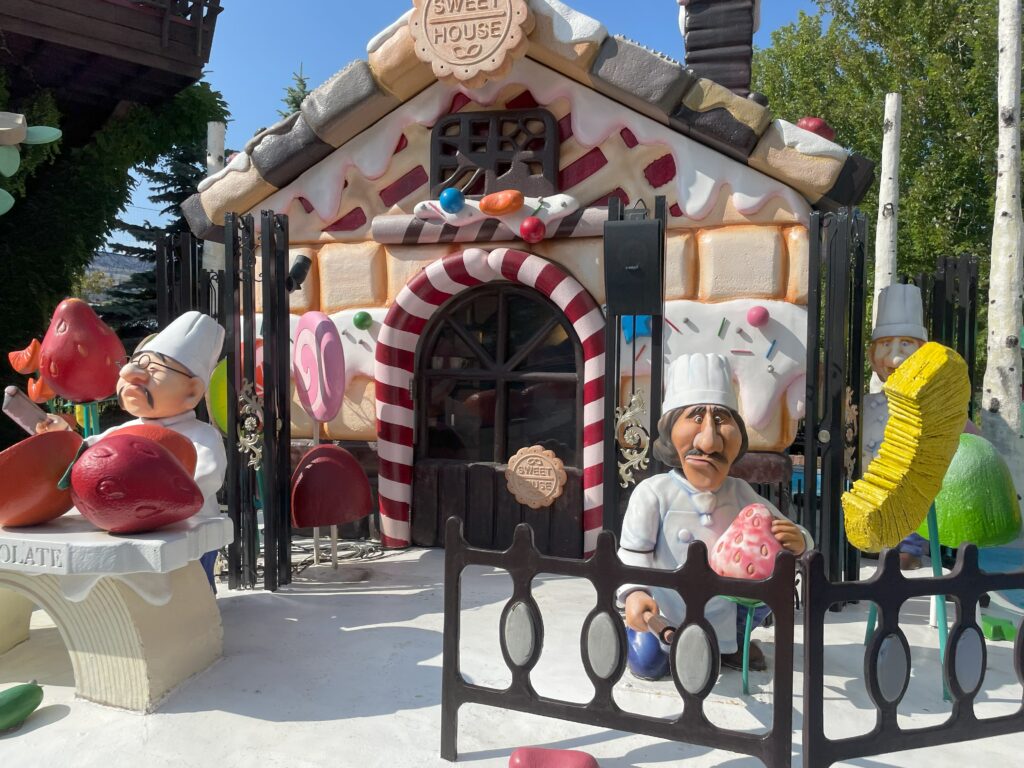 A close-up of the candy house display at Shiroi Koibito Park, featuring patissier figures holding giant sweets.