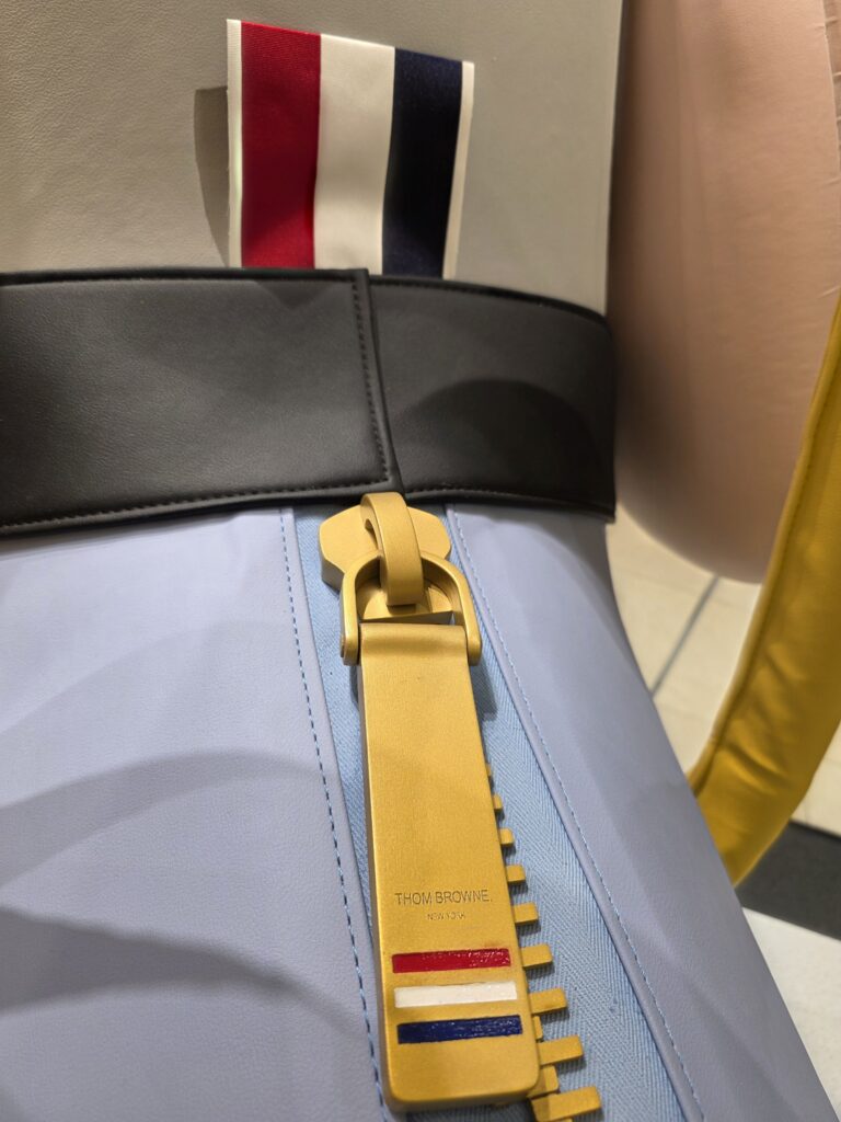 Gold zipper pull engraved with Thom Browne and tricolor