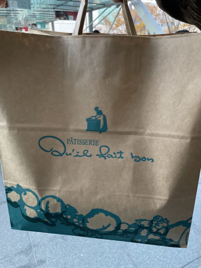 A shopping bag with the Qu'il Fait Bon logo